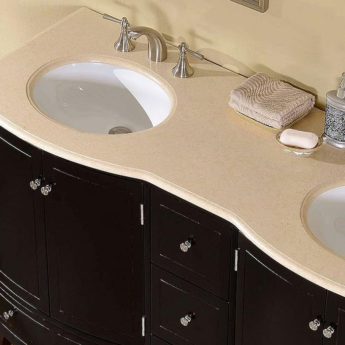 Curved black bathroom vanity with beige stone countertop, double white sinks, brushed nickel faucets, and a folded towel beside soap.