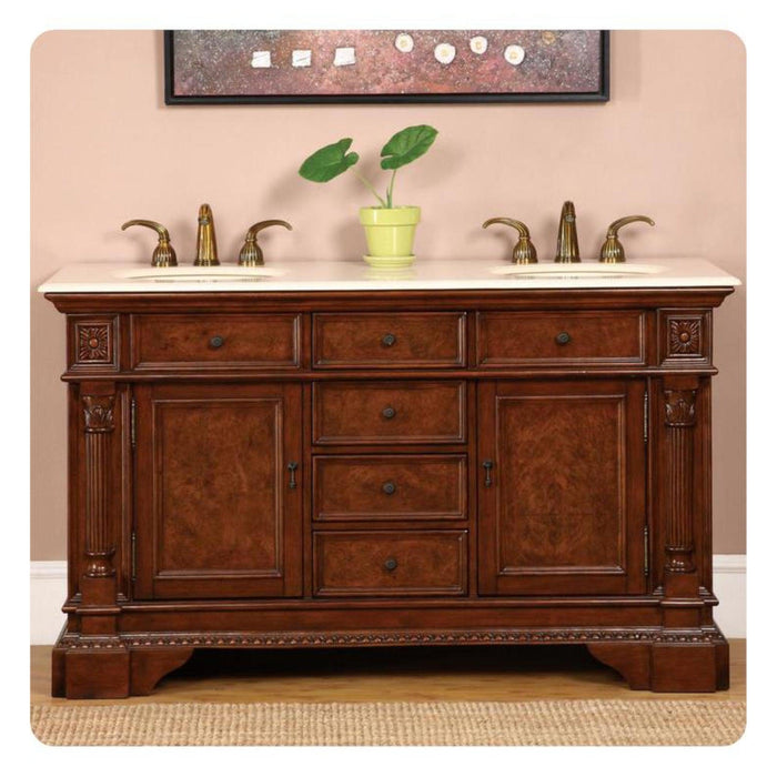 Rich wood bathroom vanity with marble top, brass fixtures, and a small green plant in a yellow pot.