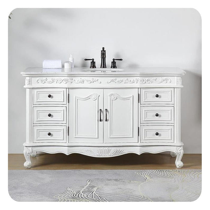 Elegant white bathroom vanity with ornate carved details, six drawers, central cabinet, and black faucet fixtures on marble countertop.