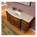 Elegant wooden bathroom vanity with white marble top, curved design, ornate carved details, and built-in oval sink with brass fixtures.