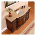 Antique wooden bathroom vanity with travertine top, white sink, ornate design, and yellow roses in decorative vase