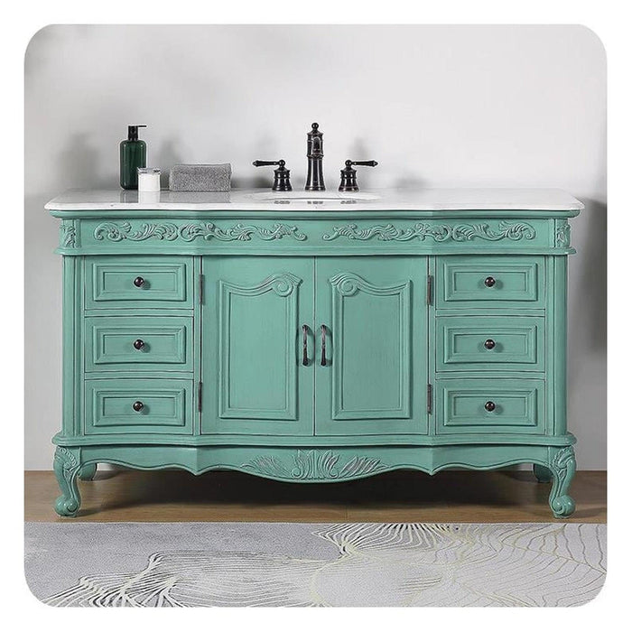 Vintage-style mint green bathroom vanity with carved details, six drawers, black fixtures, and white marble countertop.
