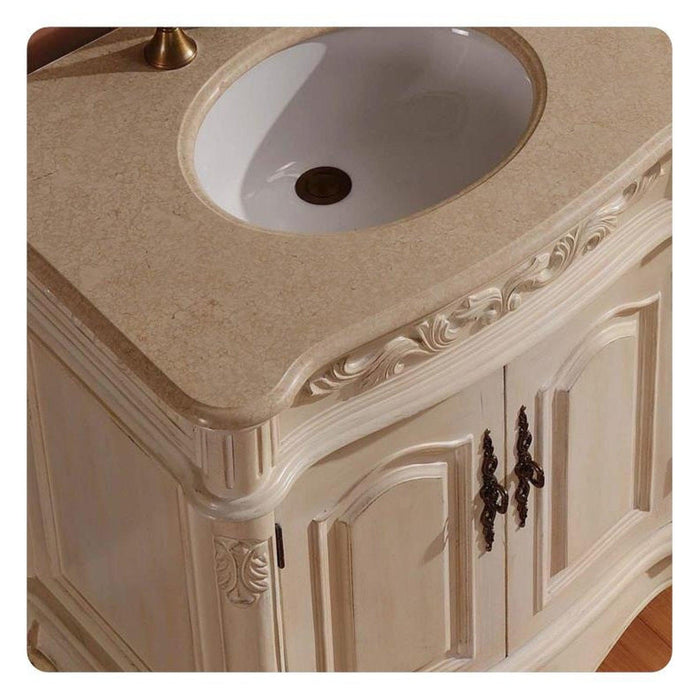 Ornate white bathroom vanity with carved details, marble countertop, and oval white sink with decorative bronze hardware.