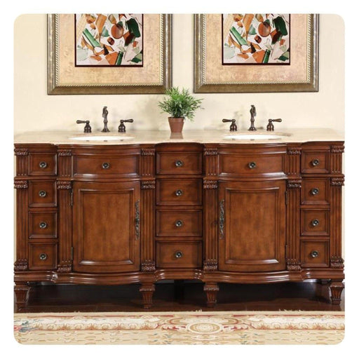 Elegant wooden double bathroom vanity with ornate carved details, two sinks, bronze fixtures, and abstract art above, with small green plant in center