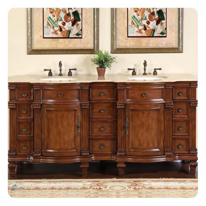 Elegant wooden double bathroom vanity with ornate carved details, two sinks, bronze fixtures, and abstract art above, with small green plant in center