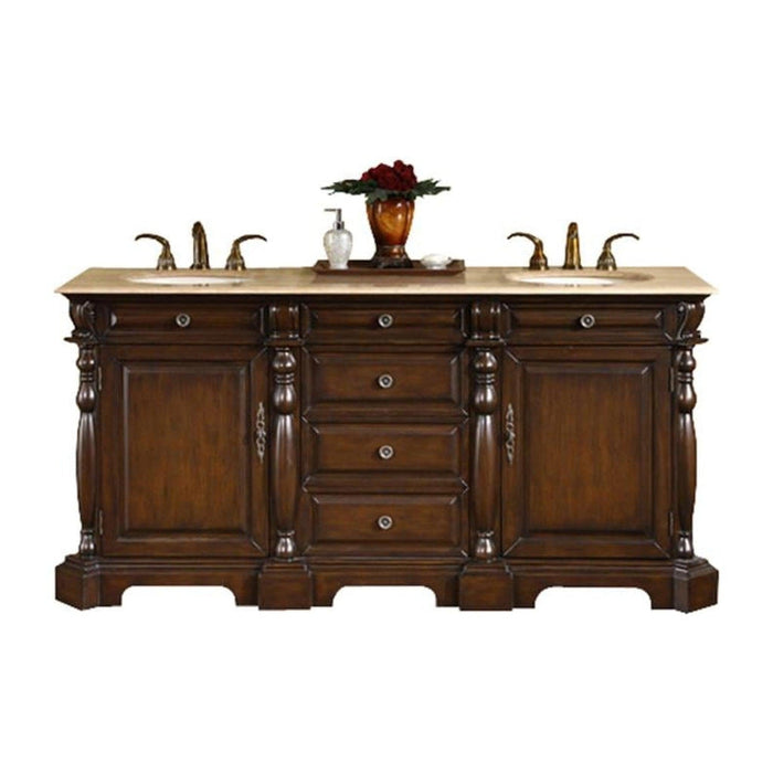 Rich mahogany bathroom vanity with marble top, featuring double sinks, decorative turned columns, and a vase of red roses.