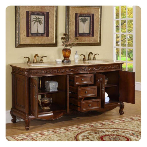 Antique wooden bathroom vanity with marble top, palm tree art, bronze faucets, and ornate design, with window showing garden view.