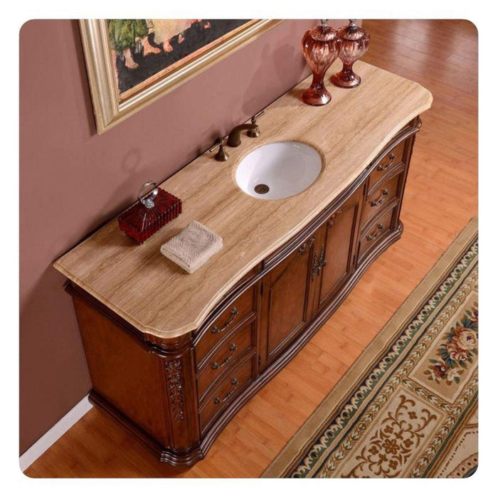 Elegant wooden bathroom vanity with curved edges, marble top, white sink, and ornate decorative glass items.