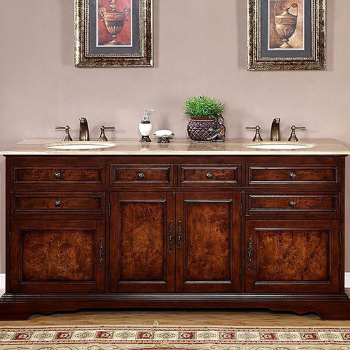 Rich wood double vanity with marble top, two sinks, and framed urn artwork above, accented by small plant and bathroom accessories.