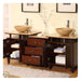 Dark wood bathroom vanity with two stone vessel sinks, drawers, open shelving, and delicate pink flowers in a vase.