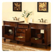 Elegant wooden bathroom vanity with double sinks, white marble top, bronze faucets, and decorative floral artwork above white lilies.