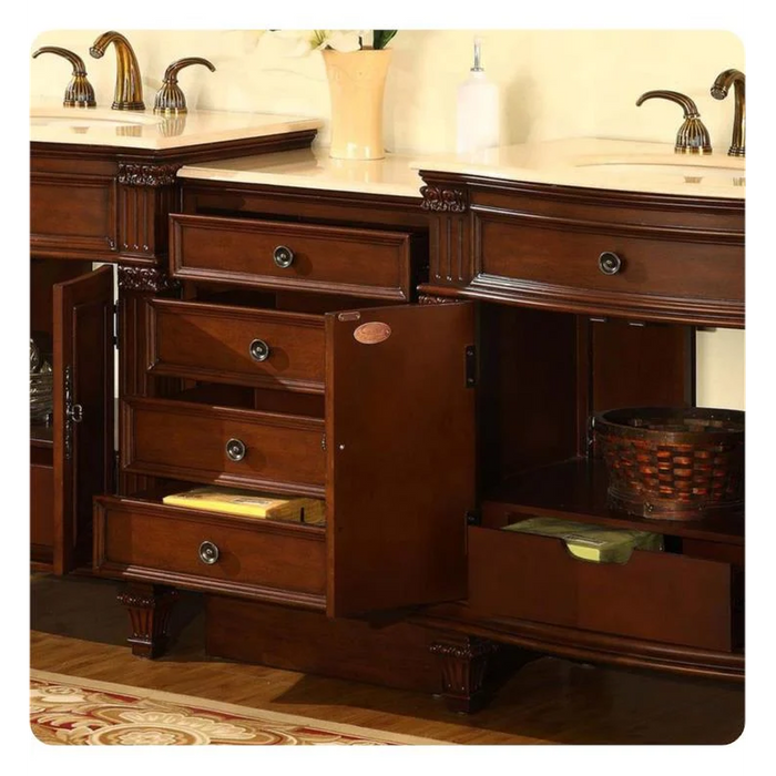 Dark wood bathroom vanity with multiple drawers, marble countertop, and ornate bronze faucets, set on an elegant patterned rug.
