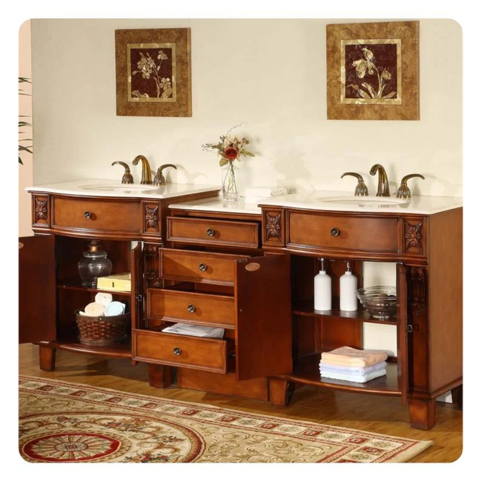 Elegant wooden bathroom vanity with double sinks, decorative drawers, floral wall art, and neatly folded towels on open shelves.