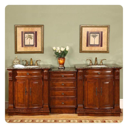 Rich wood bathroom vanity with marble top, twin sinks, and palm tree art prints flanking an amber vase with white roses.