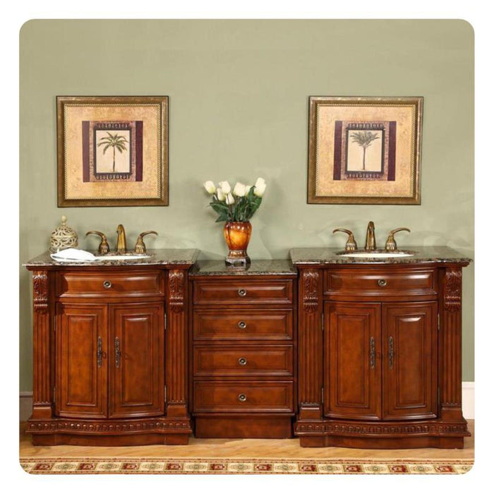 Rich wood bathroom vanity with marble top, twin sinks, and palm tree art prints flanking an amber vase with white roses.