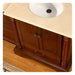 Rich wood bathroom vanity with white sink, decorative columns, and ornate cabinet hardware on hardwood floor