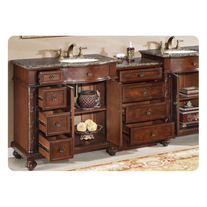 Antique wooden bathroom vanity with granite top, multiple drawers, decorative fixtures, and open shelving with ornamental objects.