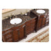 Ornate wooden bathroom vanity with Baltic brown granite countertop, two white sinks, and decorative carved details.