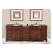 Elegant wooden double bathroom vanity with granite countertops, two sinks, and palm tree art above, mounted on ornate rug.