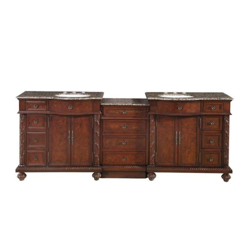 Ornate wooden bathroom vanity with rich brown finish, marble countertop, two sinks, multiple drawers and cabinets with decorative hardware.
