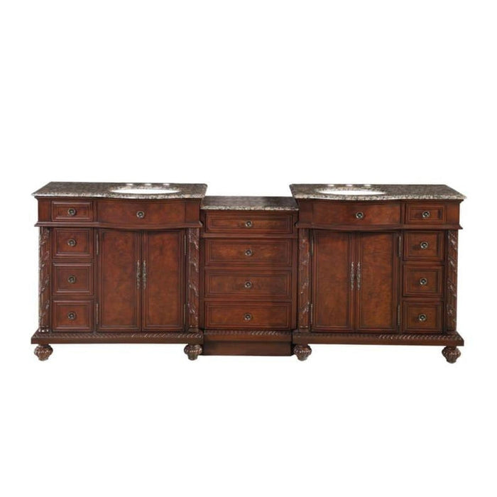 Ornate wooden bathroom vanity with rich brown finish, marble countertop, two sinks, multiple drawers and cabinets with decorative hardware.