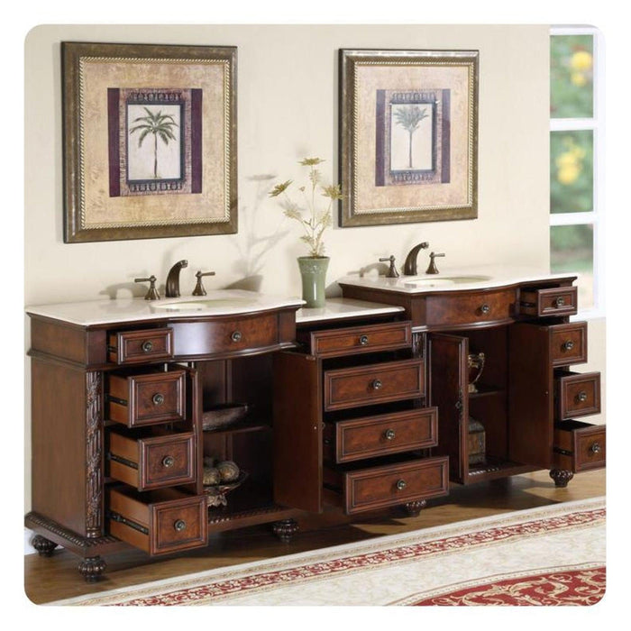 Elegant wooden bathroom vanity with multiple drawers, two sinks, and framed palm tree artwork above, set on a patterned red and cream rug.