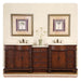 Rich wood double vanity with white sinks, framed palm tree art, and delicate vase between matching sinks on cream wall.