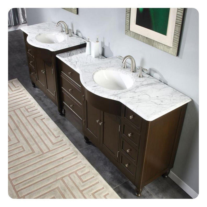 Dark wood double vanity with white marble countertop and two oval sinks, silver faucets, and decorative patterned area rug.
