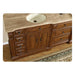 Wooden bathroom vanity with ornate drawers, central cabinets, and cream-colored stone countertop with round sink.