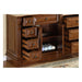 Rich wood bathroom vanity with multiple open drawers, revealing rolled white towels in a center cabinet compartment.