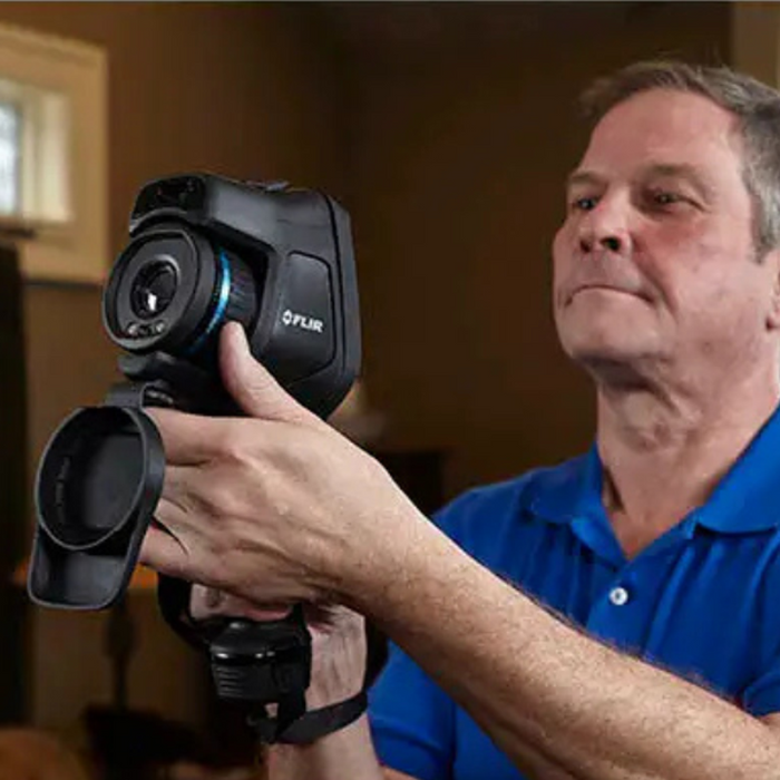 Teledyne FLIR E54 24 NIST man holding camera side view black body blue shirt.