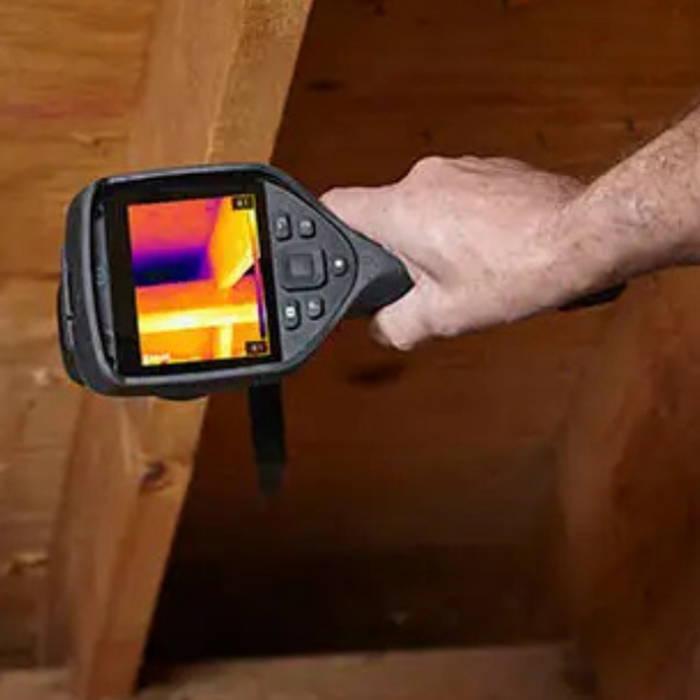 Teledyne FLIR E54 24 hand holding camera pointed at wooden attic thermal display.