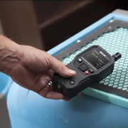 Teledyne FLIR MR176 Imaging Moisture Meter Plus with IGM Technology and Lepton Image Detector hand holding device on blue surface.