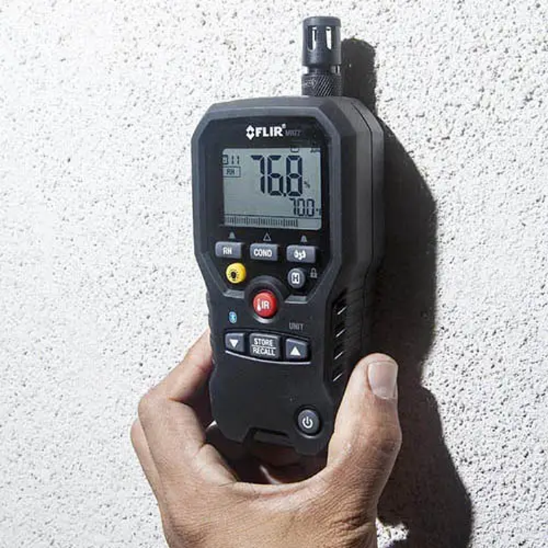 Teledyne FLIR MR77 5 In 1 Moisture Meter hand holding device measuring wall.
