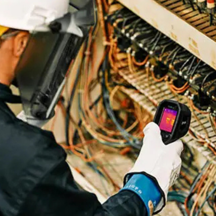 Teledyne FLIR TG165 X electrician scanning wiring panel with thermal camera.