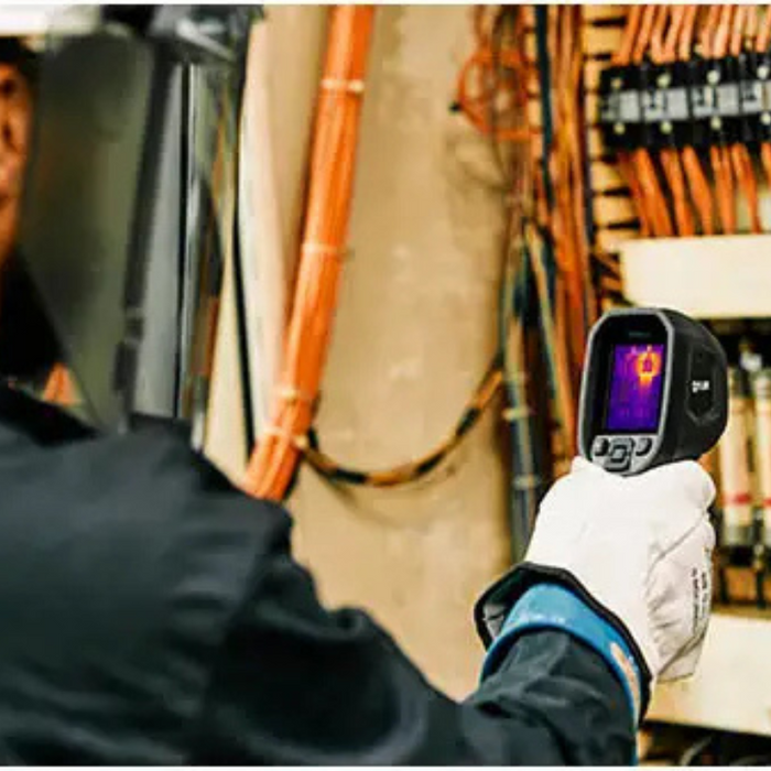 Teledyne FLIR TG165 X electrician using thermal camera on control panel.