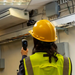 Teledyne FLIR TG54 2 spot thermometer worker in hardhat aiming at ac unit.