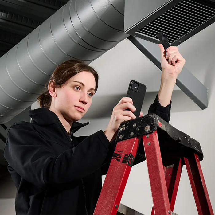 Teledyne Flir A70 Rd Kit 51 woman on ladder using camera to inspect vent.