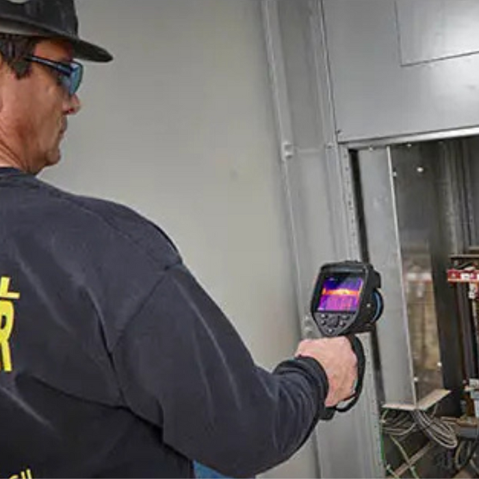 Teledyne Flir E76 42 technician scanning electrical panel with thermal camera.