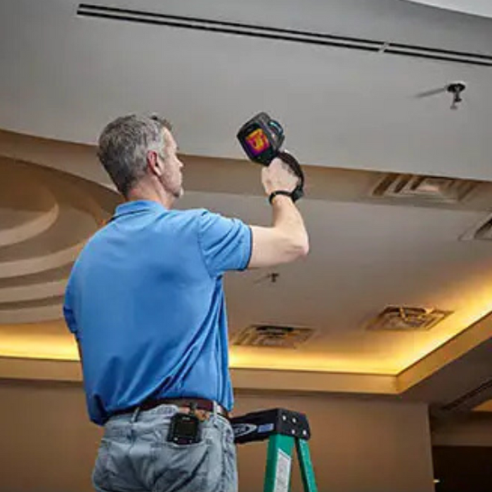 Teledyne Flir E86 24 14 42 Nist person on ladder inspecting ceiling with thermal camera.
