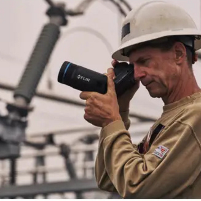 Teledyne Flir T865 24 6 technician using camera in field wearing hardhat.