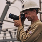 Teledyne Flir T865 42 Nist technician using camera on site with power lines.