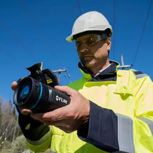 Teledyne Flir T865 Dfov worker using camera front view outdoors hard hat.