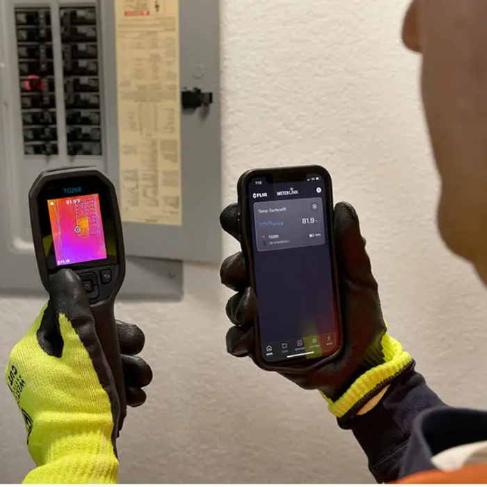 Teledyne Flir Tg268 electrician scanning panel and holding phone with app.