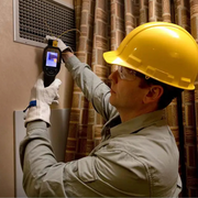 Teledyne Flir Tg298 technician using camera on air vent with hard hat.