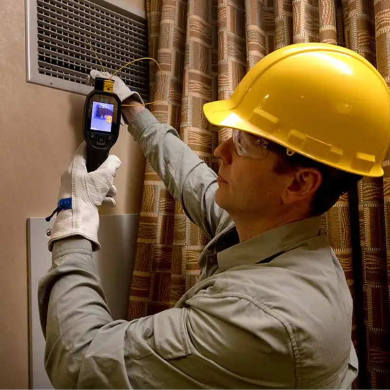 Teledyne Flir Tg298 technician using camera on air vent with hard hat.