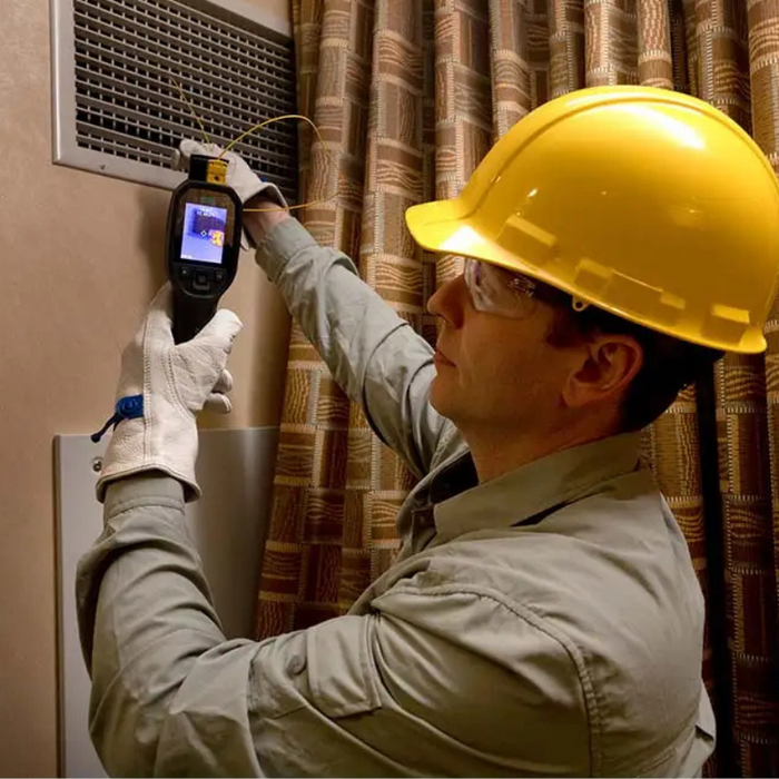 Teledyne Flir Tg298 technician using camera on air vent with hard hat.