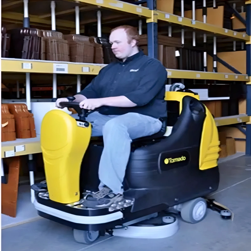 Tornado BD 28 27 Ride On Automatic Floor Scrubber in use person riding warehouse.