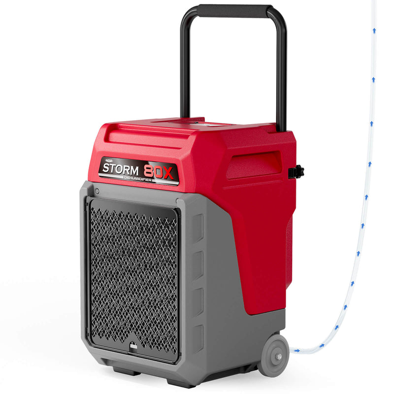 AlorAir Storm 80X in red and gray, front three-quarter view with its handle raised and drain hose attached