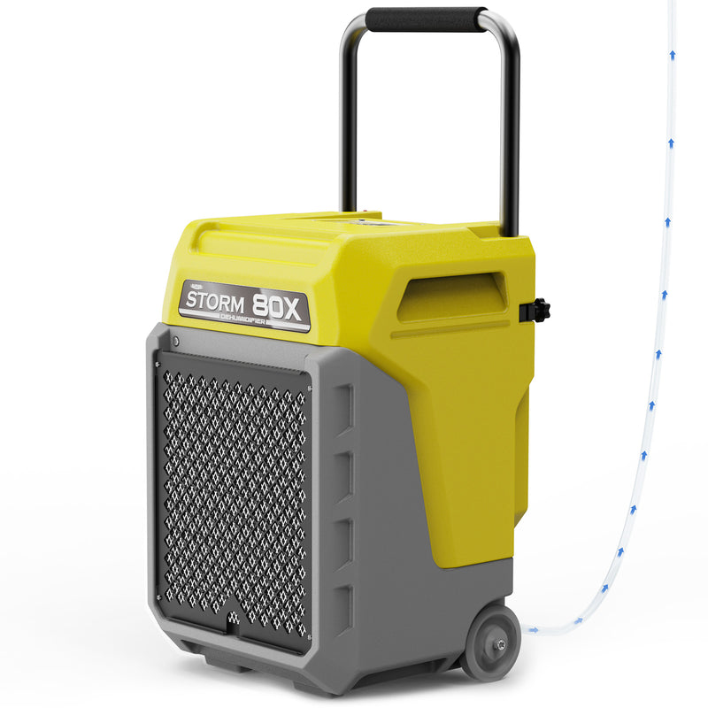 AlorAir Storm 80X in yellow and gray, front three-quarter view with its handle raised and drain hose attached
